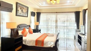 A hotel room with a large bed, two bedside tables with lamps, a TV, and a window with curtains.