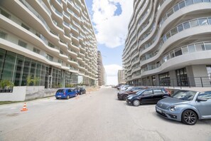A modern apartment building with multiple balconies and a parking area with cars. - Casa Del Mar 2 (Navodari)