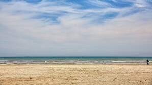 A beach with a clear sky and a person walking on the sand. - Casa Del Mar 2 (Navodari)