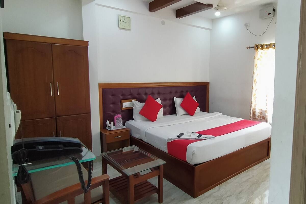 Quarto com uma cama, escrivaninha, telefone e guarda-roupa.