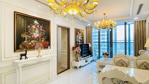 Un salón lujoso con candelabros ornamentales, un cuadro floral grande y un televisor moderno.