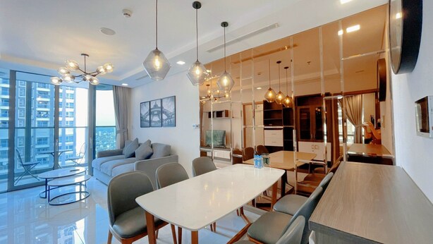 Un interior moderno con zona de comedor, sofá y ventanas amplias con vistas a la ciudad.