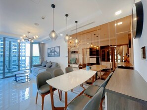 Un interior moderno con zona de comedor, sofá y ventanas amplias con vistas a la ciudad.