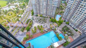 Un edificio residencial alto con varios balcones, un patio central con piscina y zonas verdes circundantes.