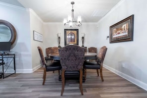 Enjoy meals in this dining area with a round table and six comfortable chairs, surrounded by artwork and a chandelier.