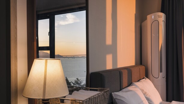 Ein Hotelzimmer mit Bett, Lampe, Korbwannen und Meerblick.