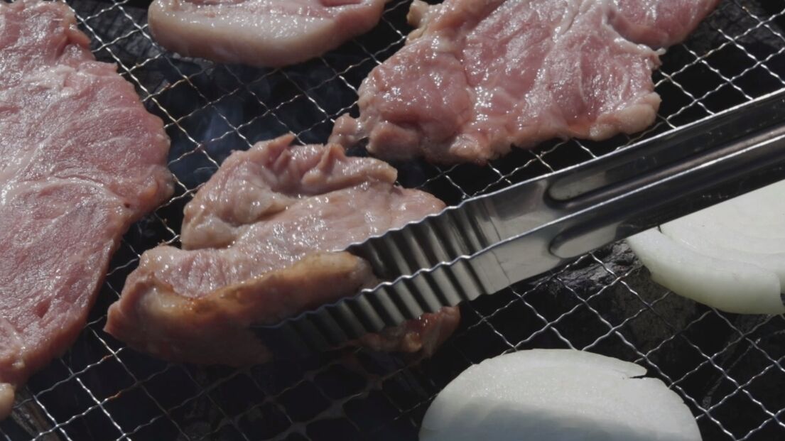 Raw meat being grilled on a wire rack.