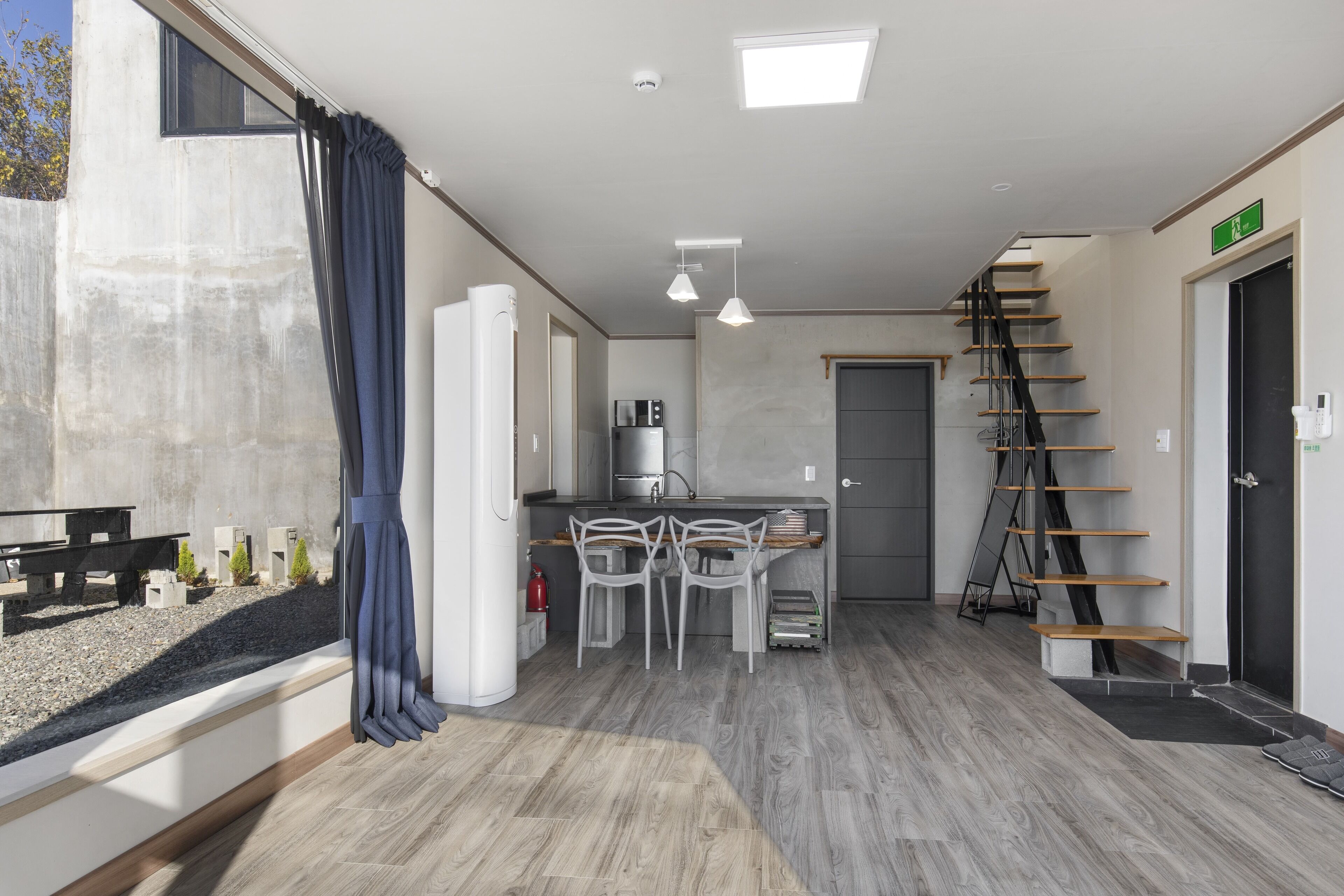 A modern kitchen with a dining area, a staircase, and a view of the outside.