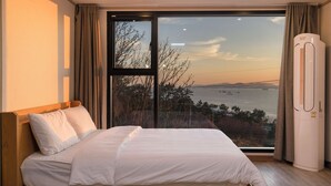 Ein Schlafzimmer mit großem Fenster, einem Bett und einer Klimaanlage.