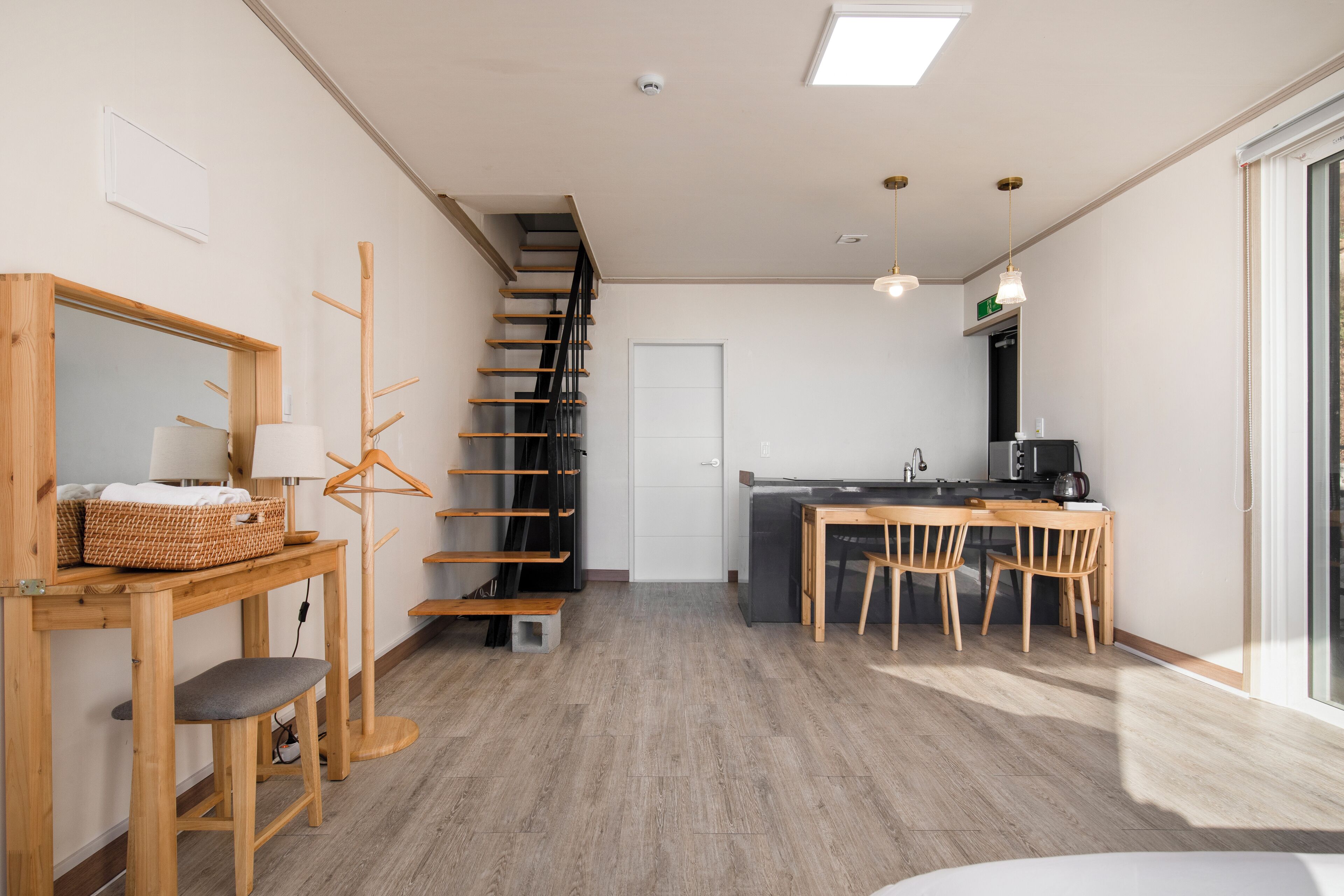 A modern kitchen with a dining area, wooden flooring, and a staircase leading to another level.