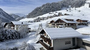 A snow-covered mountain village with chalet-style buildings, a ski slope, and a clear sky. - Appartement Mittelberg in Aparthotel, Kleinwalsertal, Summer & Winter Sports

 (Mittelberg)