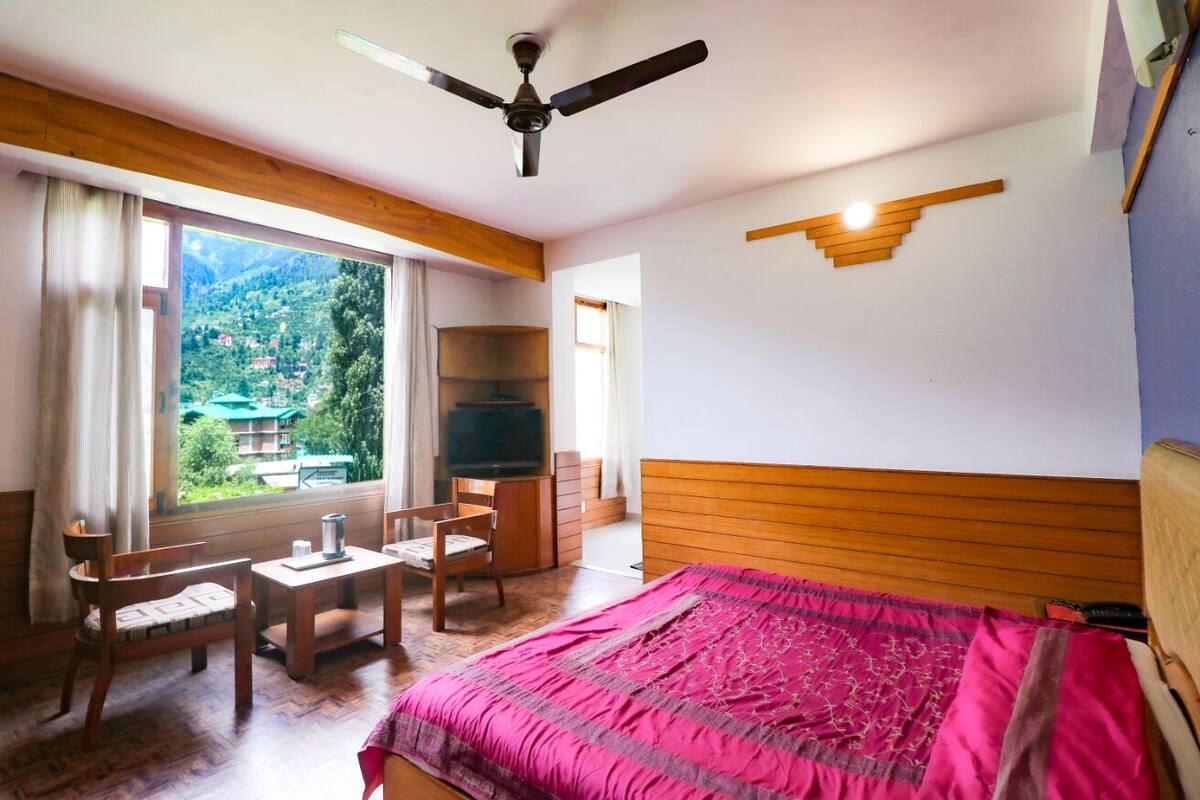 Una camera da letto con un letto, una scrivania, una sedia, una televisione e vista su un paesaggio montano.