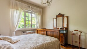 A bedroom with a large bed, a wooden dresser, a mirror, and a radiator. - Holiday Apartment 'Tea Rose House' with Terrace, Shared Garden & Wi-Fi (Capannori)
