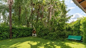 A lush garden with a bench, a small structure, and dense foliage. - Holiday Apartment 'Tea Rose House' with Terrace, Shared Garden & Wi-Fi (Capannori)