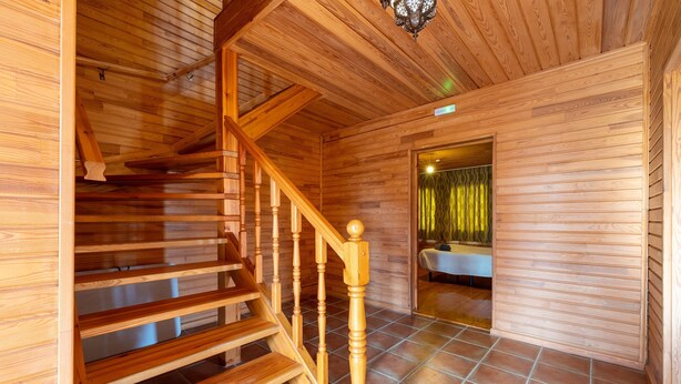 Un interior de madera con una escalera, un baño con cortina y un suelo de baldosas.
