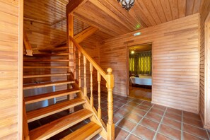 A wooden interior with a staircase, a bathroom with a curtain, and a tiled floor.