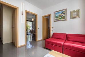 Een moderne woonkamer met een rode bank, houten deuren en een schilderij aan de muur.