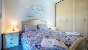 A bedroom with a bed, nightstands, a ceiling fan, a wardrobe, and a wall art piece. - Holiday Speed Apartment with Mountain View, Private Terrace, and Wi-Fi (Arco)