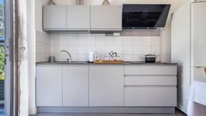 A modern kitchen with white cabinets, a built-in oven, and a large window. - Holiday Speed Apartment with Mountain View, Private Terrace, and Wi-Fi (Arco)