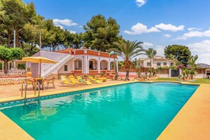 A swimming pool with sun loungers, a covered seating area, and a building with arched windows. - Villa 'Maria Beach' with Private Pool, Wi-Fi and Air Conditioning (MORAIRA)