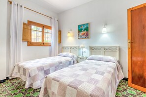 A room with two beds, a wooden door, a window with curtains, a wall-mounted lamp, and a painting. - Villa 'Maria Beach' with Private Pool, Wi-Fi and Air Conditioning (MORAIRA)