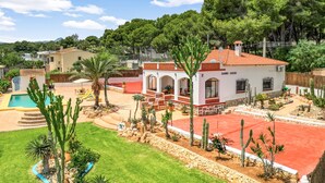 Propiedad residencial con piscina, cactus y techo de tejas rojas.