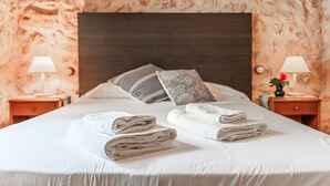A neatly made bed with folded towels, a dark headboard, and two bedside lamps on wooden nightstands.