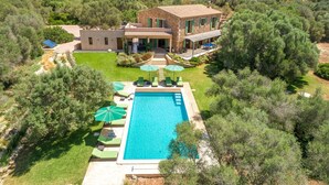 Eine Villa mit Swimmingpool, umgeben von Grün und Bergen im Hintergrund.