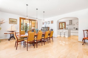 A dining area with a wooden table and chairs, a chandelier, and a view of the kitchen. - Villa 'Los Hibiscus' with Mountain View, Wi-Fi and Air Conditioning (Felanitx)