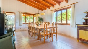 Comedor con mesa de madera, sillas e iluminación colgante.