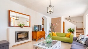 Una sala de estar con chimenea, sofá, mesa de centro y una escalera.