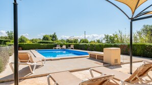 Una piscina con sillones de descanso y una zona cubierta.