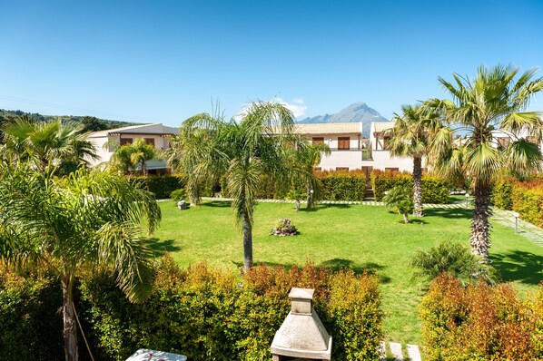 A hotel with a well-maintained lawn, palm trees, and a mountain in the background.