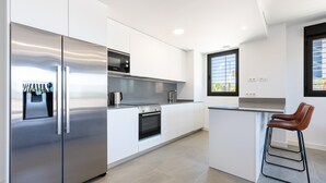 Una cocina moderna con electrodomésticos de acero inoxidable, armarios blancos y un taburete de bar.