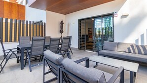 Un patio al aire libre con una mesa de comedor, sillas y un sofá.