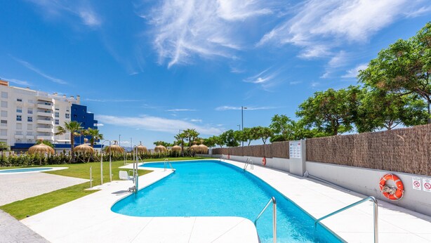 Una piscina con muelle blanco, palmeras y un flotador en la pared.