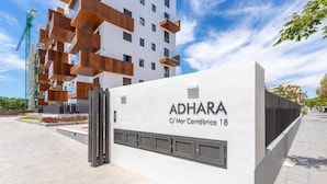Un edificio moderno con el nombre 'ADHARA' y un cartel que indica 'C/ Mar Cantábrico 18'.