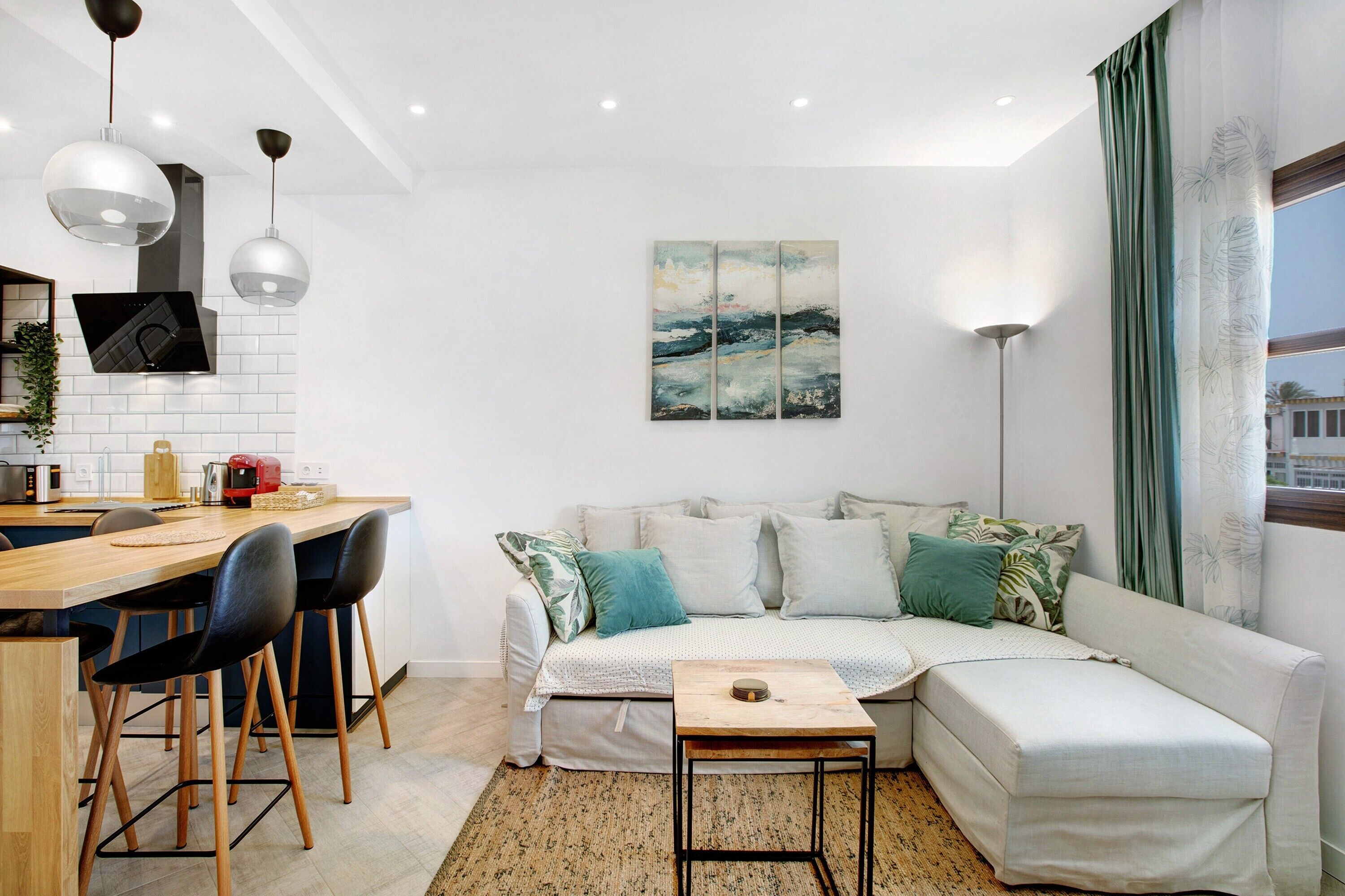 Un espacio habitable moderno con cocina, sofá y una mesa de comedor con sillas.