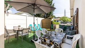 Une terrasse extérieure avec une table, des chaises et un grand parasol.