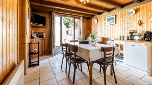 Un intérieur en bois comprenant une table à manger, des chaises, un téléviseur et un coin cuisine.