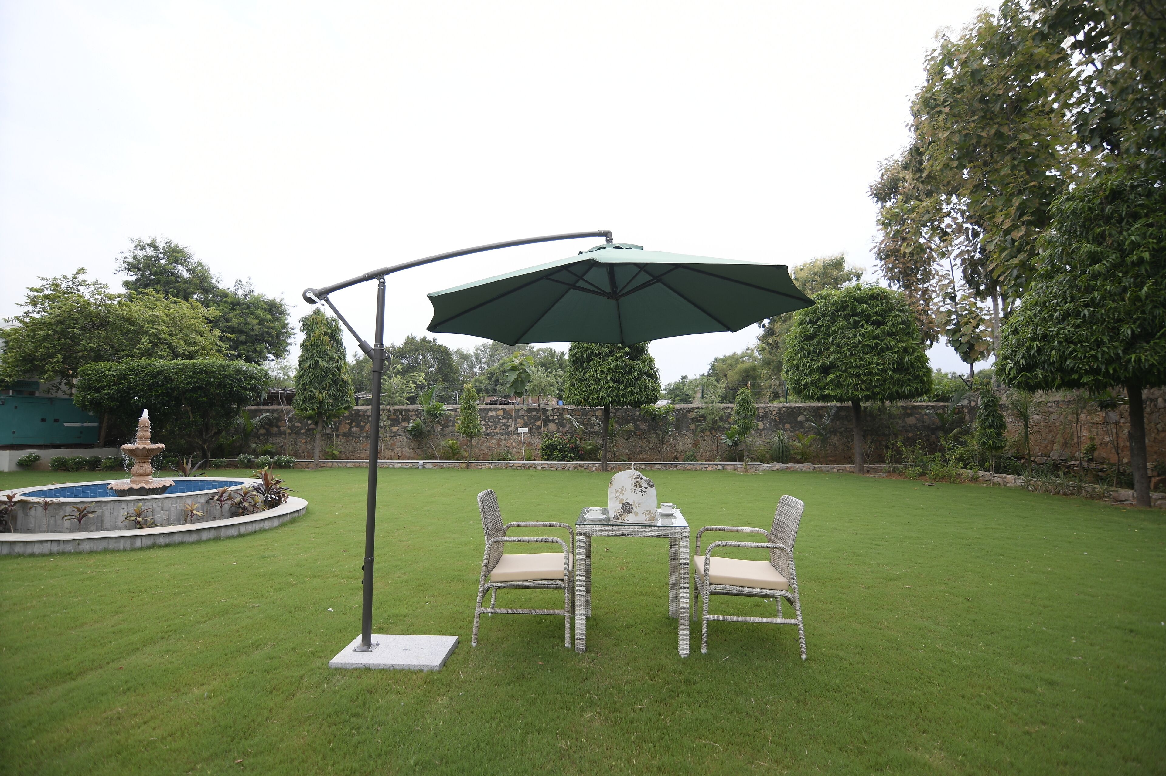 A patio with a table and chairs, a fountain, and a stone wall in the background.