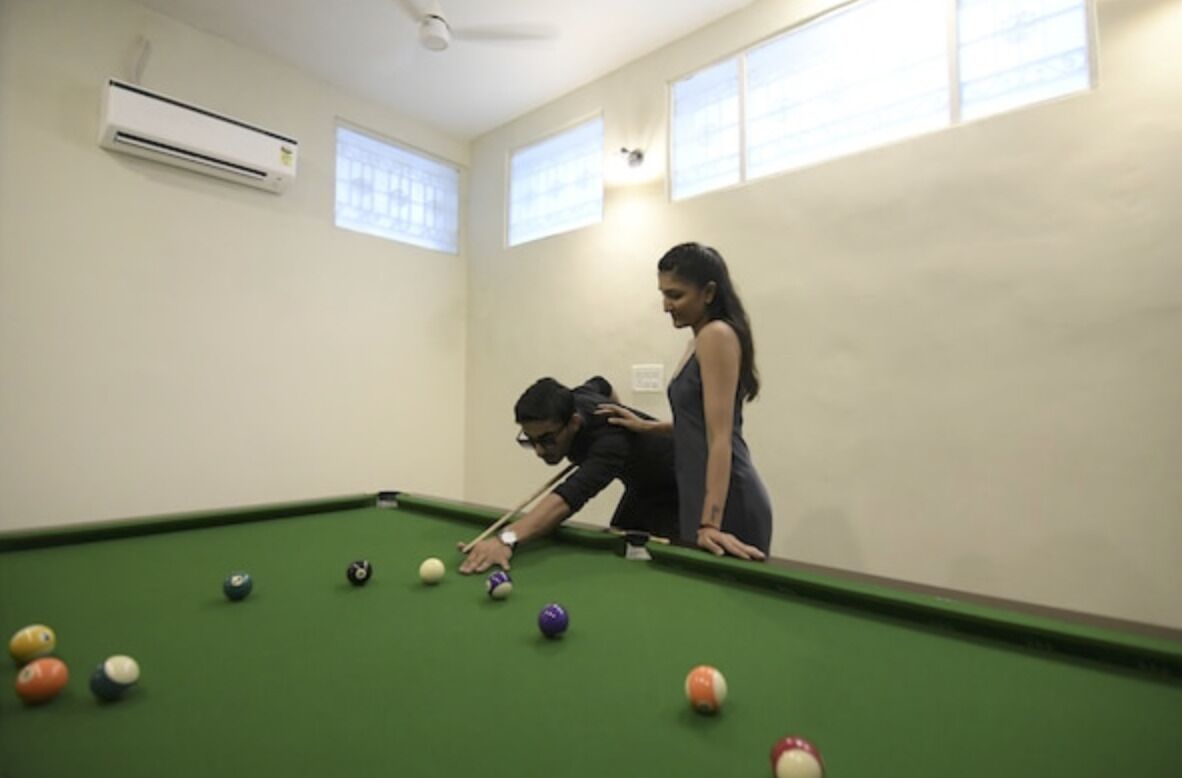 A pool table with balls, a ceiling fan, and a window with blinds.