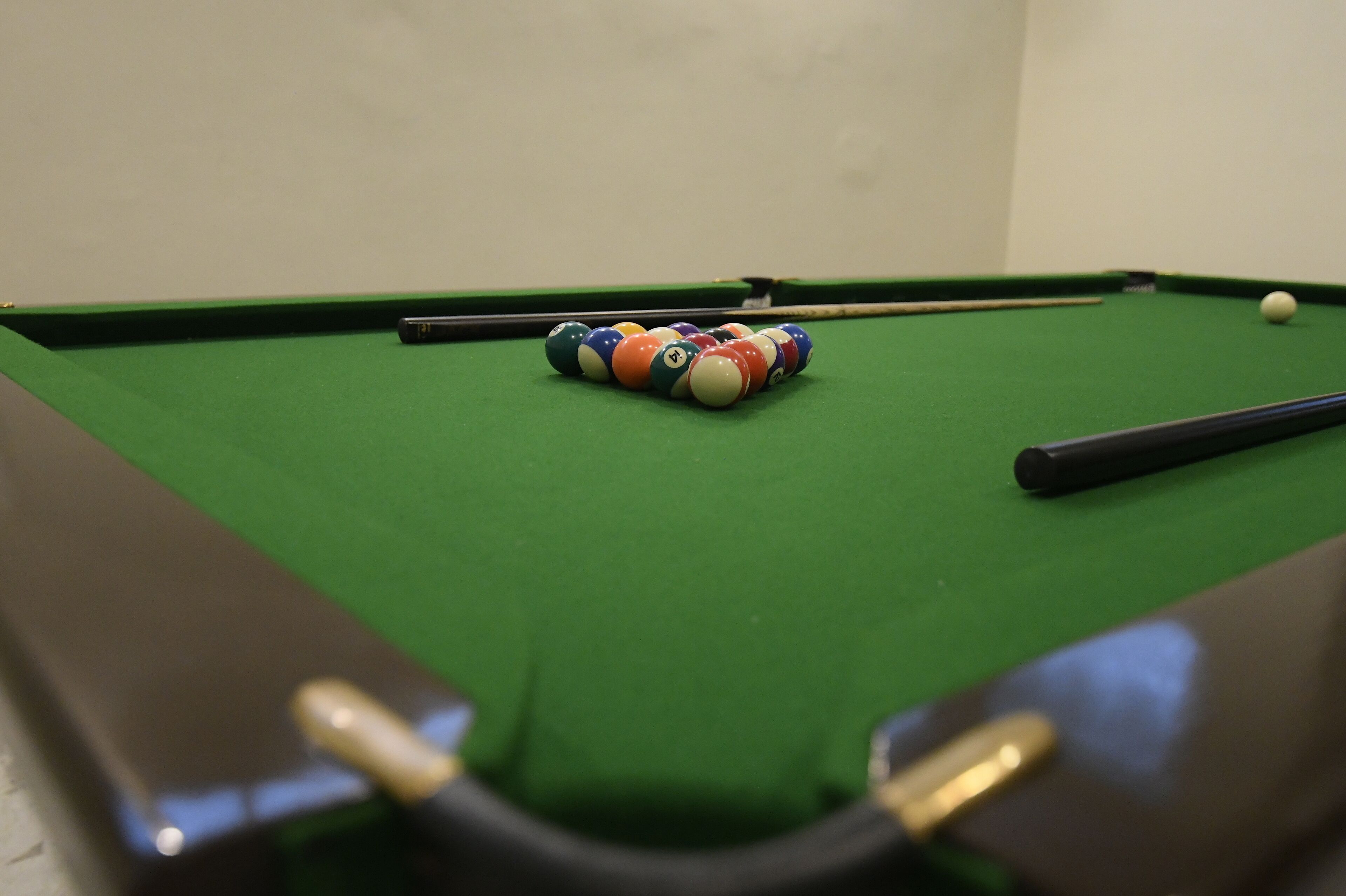 A pool table with balls and a cue stick.