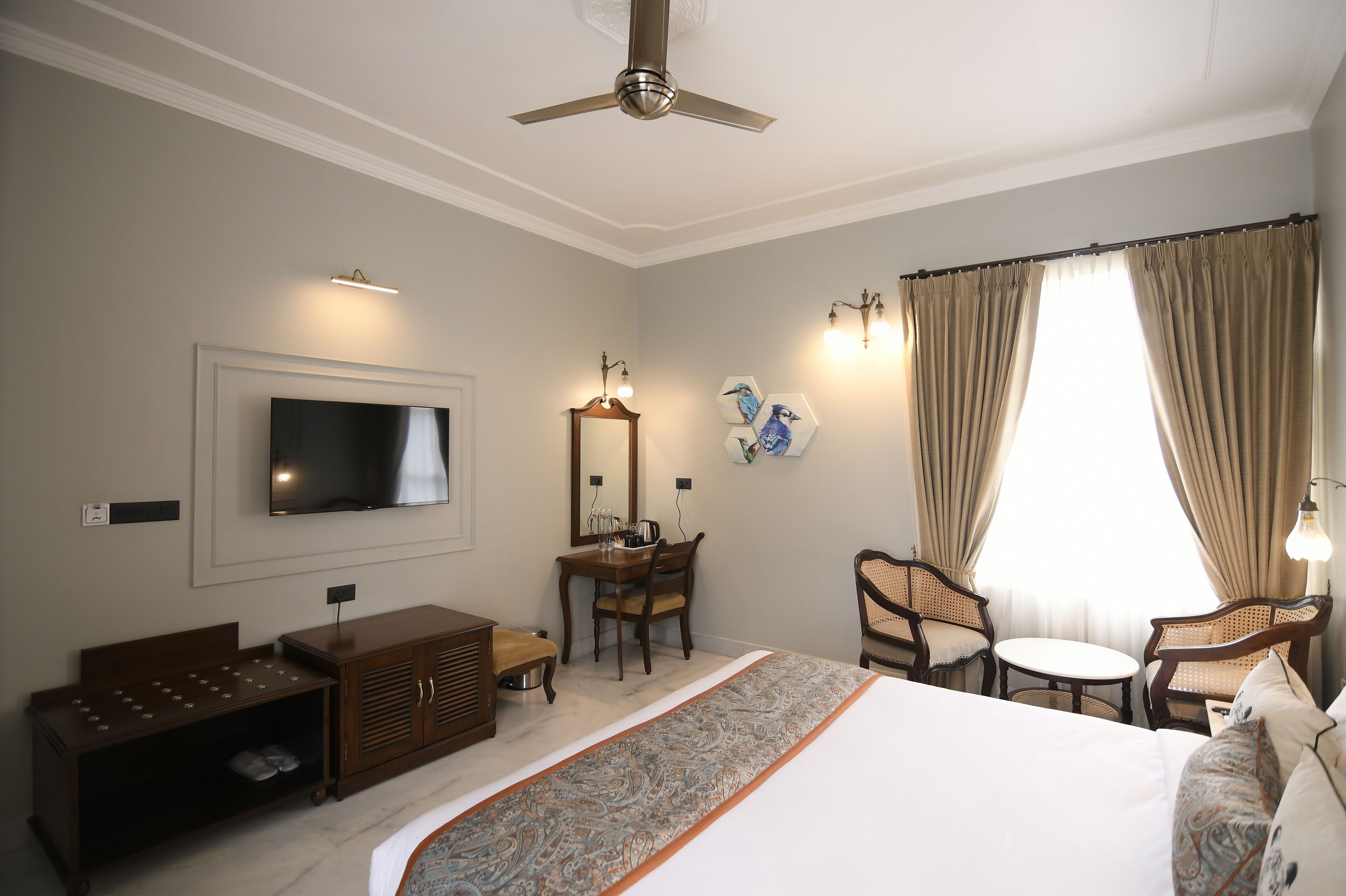 A hotel room with a bed, a TV, a desk, a chair, and a window with curtains.