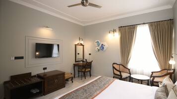 A hotel room with a bed, a TV, a desk, a chair, and a window with curtains.