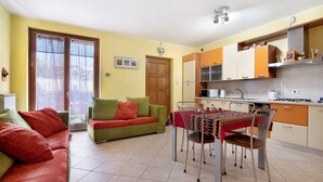 Una sala de estar con un sofá, una mesa de comedor con sillas y una zona de cocina con armarios y electrodomésticos.