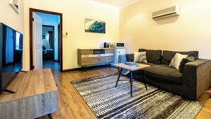 Una sala de estar moderna con un sofá, una mesita de centro, un televisor, un microondas y un cuadro en la pared.