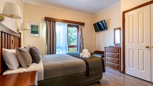 Una habitación de hotel con una cama, un tocador, un televisor y una puerta.