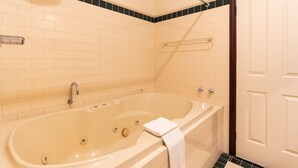 Un baño con una bañera grande, un perchero para toallas y una puerta.