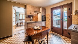 Une cuisine avec des meubles en bois, une table à manger avec un plateau, et une vue à travers la porte.